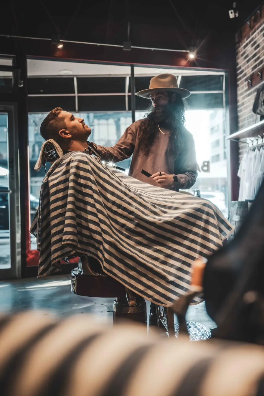 A barber finishing a client’s haircut by the window