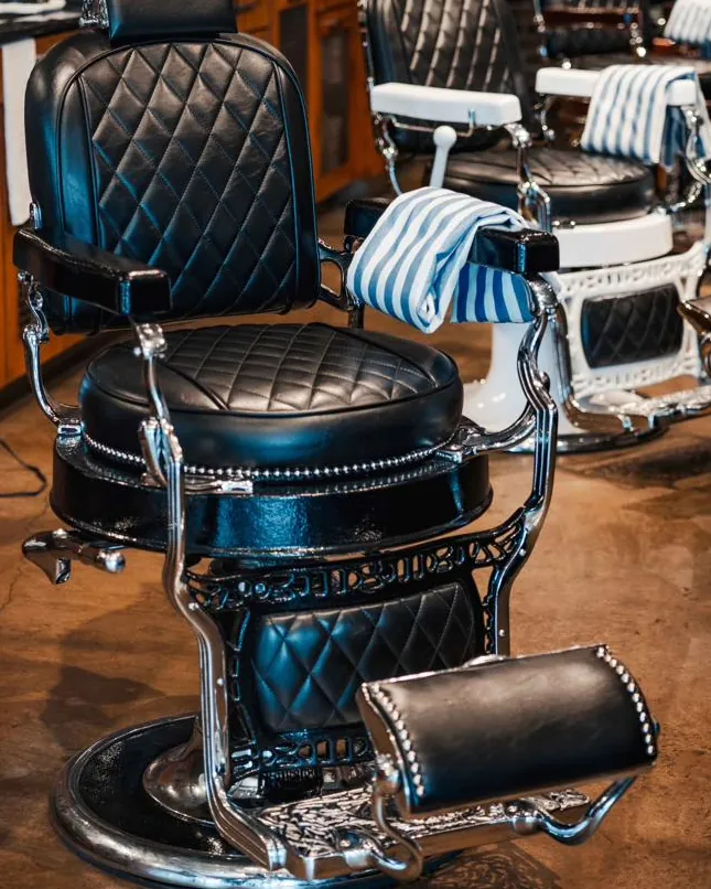 A black leather barber chair in the row of chairs