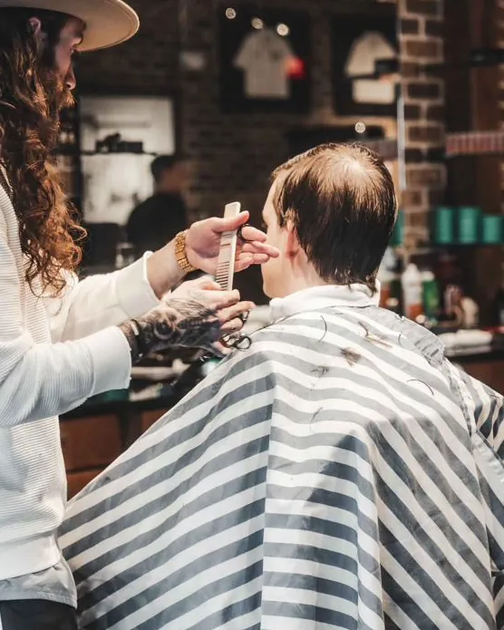 A barber working on the back of a client’s haircut