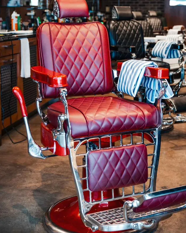 A red leather barber chair in the row of chairs