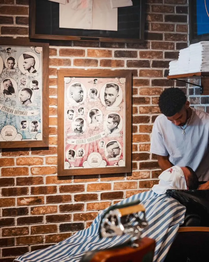 A barber at the wash basin beneath stacked towels
