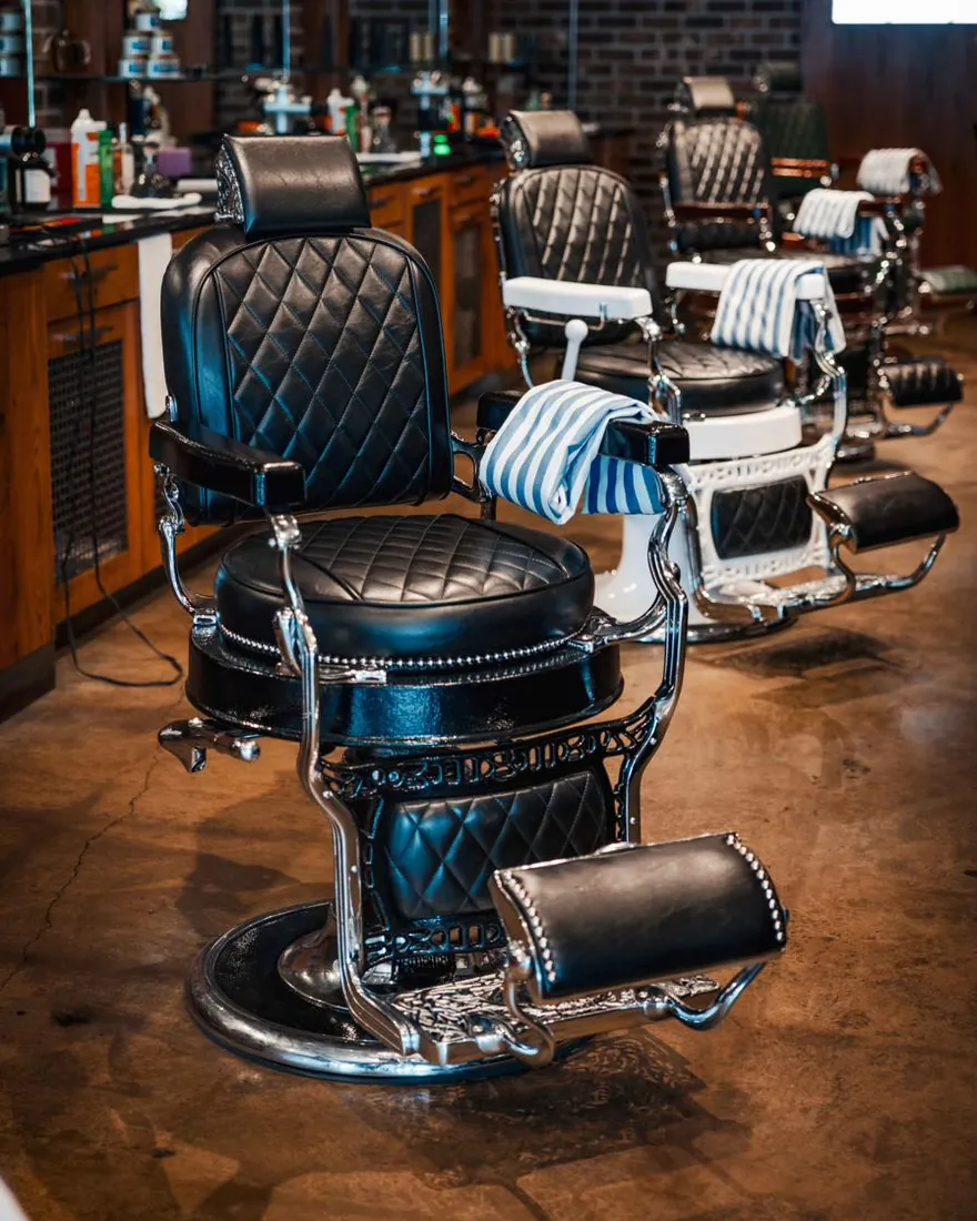 A black leather barber chair in a row of chairs