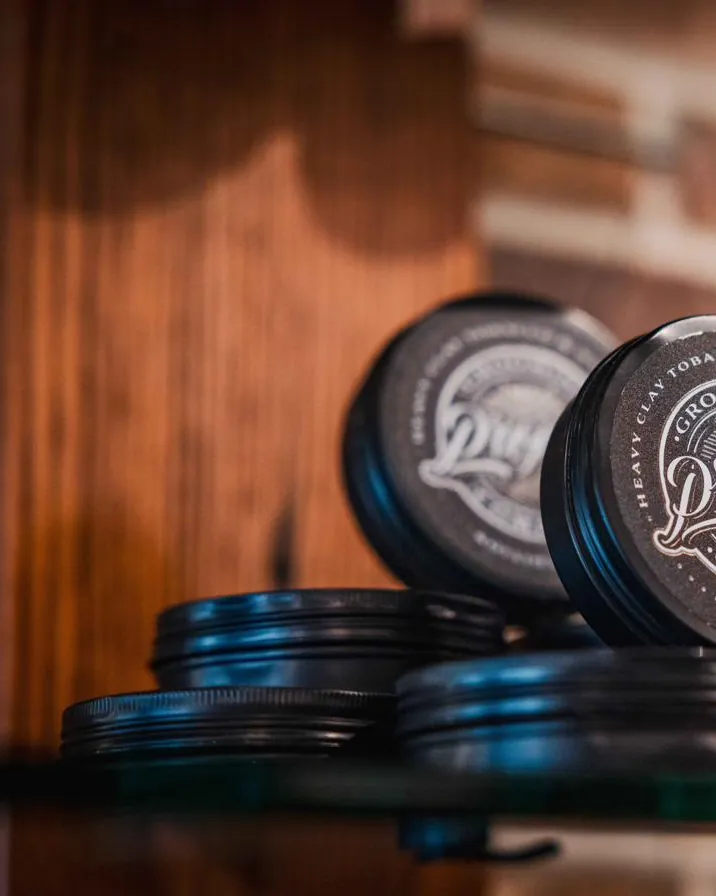 Tins of hair pomade stacked on a shelf