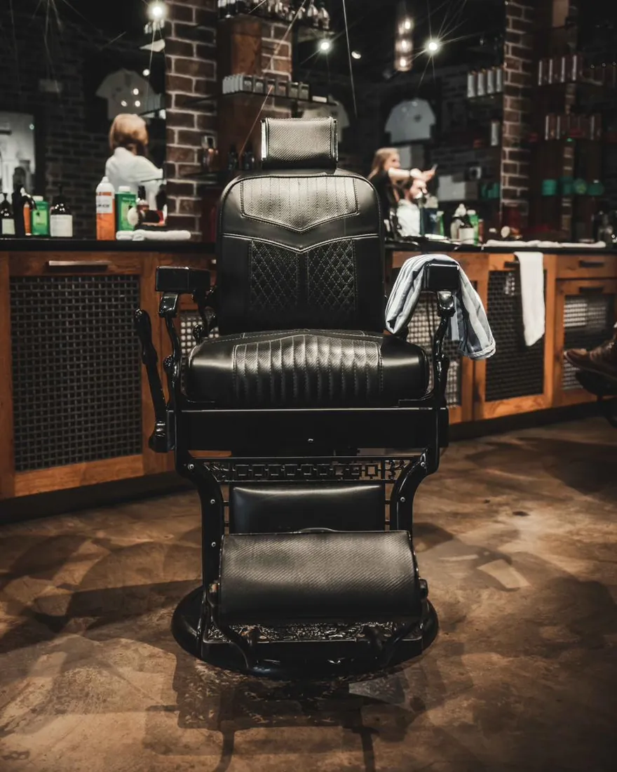 A black leather barber chair under string lights