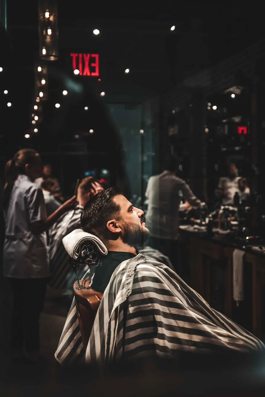 A bearded client leaning back in the barber chair at City Barbers